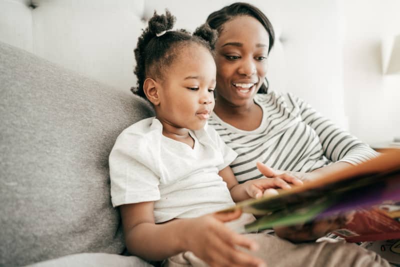 Mother reading to her toddler on couch